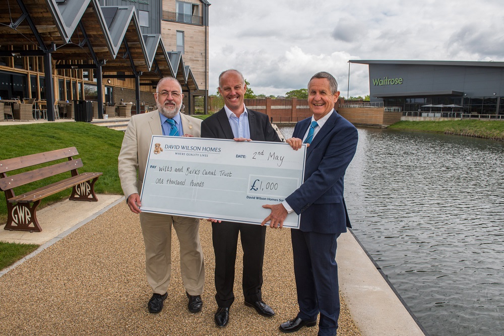 Presenting charity cheque by canal in front of pub